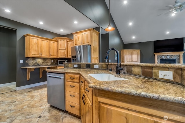 kitchen with ceiling fan, sink, light stone counters, vaulted ceiling, and appliances with stainless steel finishes