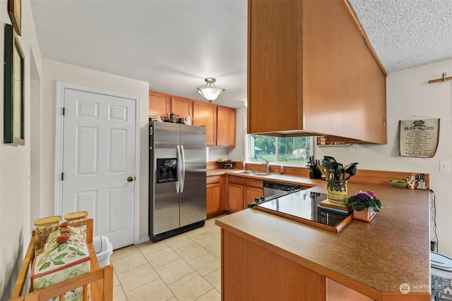 kitchen with kitchen peninsula, a textured ceiling, stainless steel appliances, sink, and light tile patterned flooring