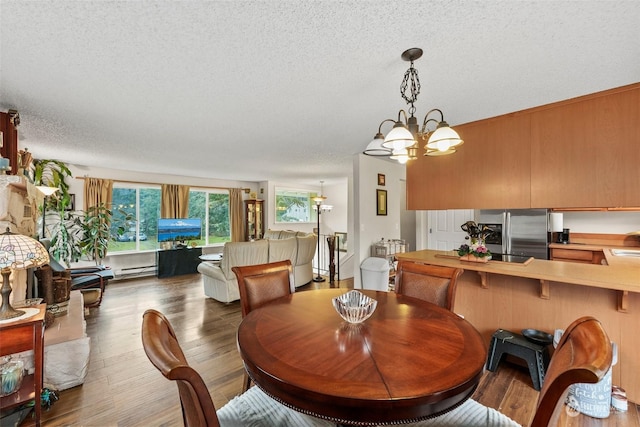 dining room featuring a textured ceiling, hardwood / wood-style flooring, an inviting chandelier, and baseboard heating