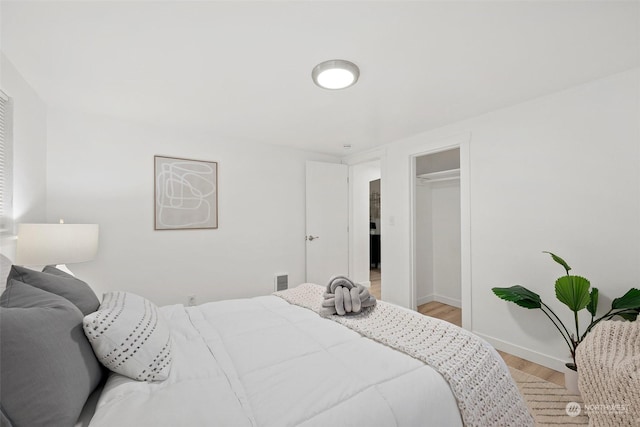 bedroom with a closet, light hardwood / wood-style floors, and a spacious closet