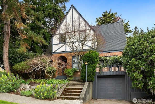 tudor house with brick siding, roof with shingles, and an attached garage