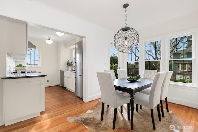 dining room with baseboards, light wood-style floors, a healthy amount of sunlight, and ornamental molding