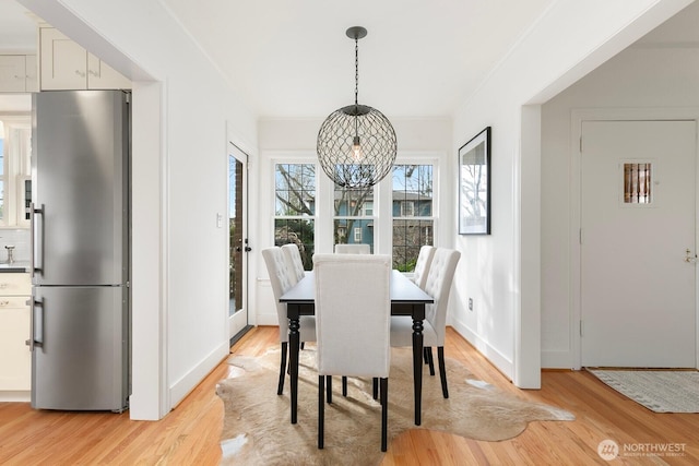 dining room with baseboards, crown molding, and light wood finished floors