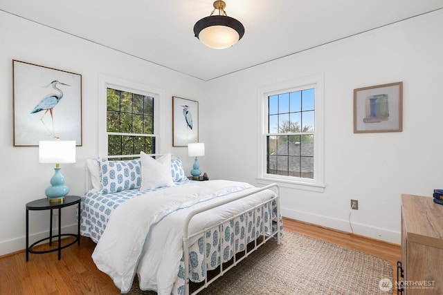 bedroom featuring multiple windows, baseboards, and wood finished floors