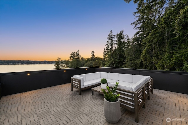 patio terrace at dusk featuring outdoor lounge area and a water view