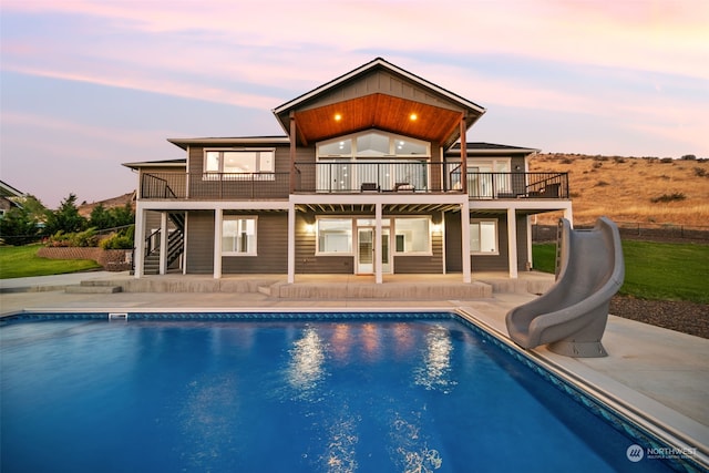 back house at dusk with a balcony and a patio