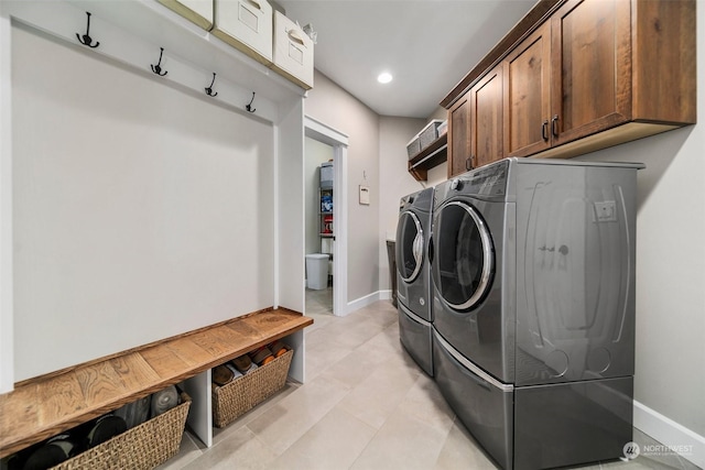 clothes washing area with cabinets and separate washer and dryer