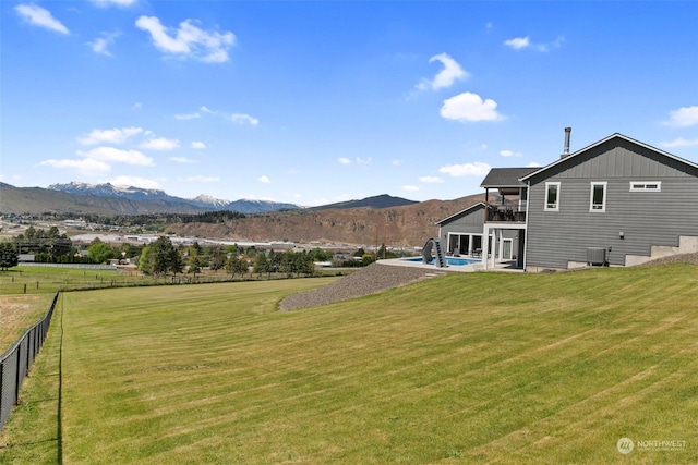 exterior space with a balcony, central AC unit, a patio area, a mountain view, and a yard