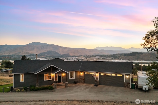 11 Holcomb Dr, East Wenatchee, WA 98802 - view of front of property featuring a mountain view, a garage, driveway, and stone siding