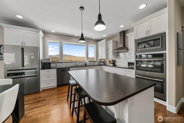 11 Holcomb Dr, East Wenatchee, WA 98802 - kitchen featuring stainless steel appliances, wall chimney exhaust hood, dark countertops, decorative backsplash, and recessed lighting