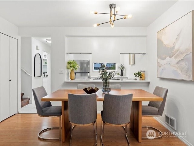 dining space with light hardwood / wood-style flooring and a notable chandelier