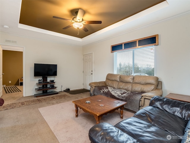 living room featuring carpet, ceiling fan, ornamental molding, and a tray ceiling