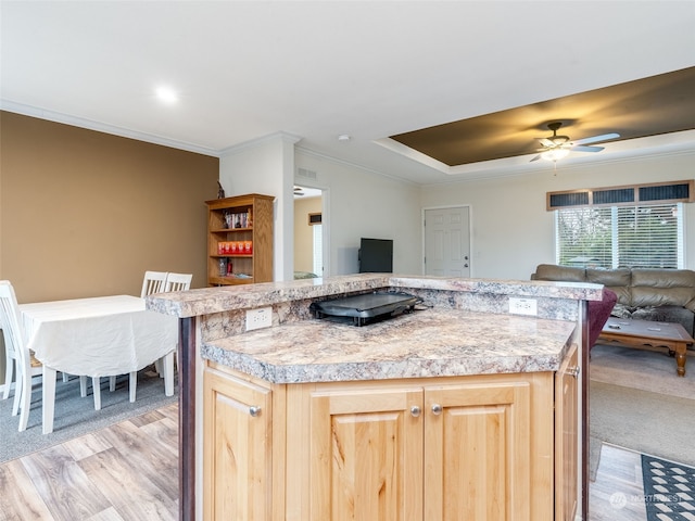 kitchen featuring ceiling fan, light brown cabinets, light carpet, a kitchen island, and ornamental molding