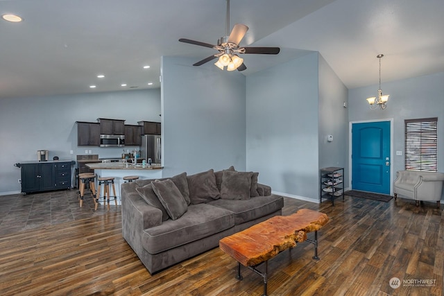 living room featuring ceiling fan with notable chandelier, dark hardwood / wood-style flooring, and vaulted ceiling