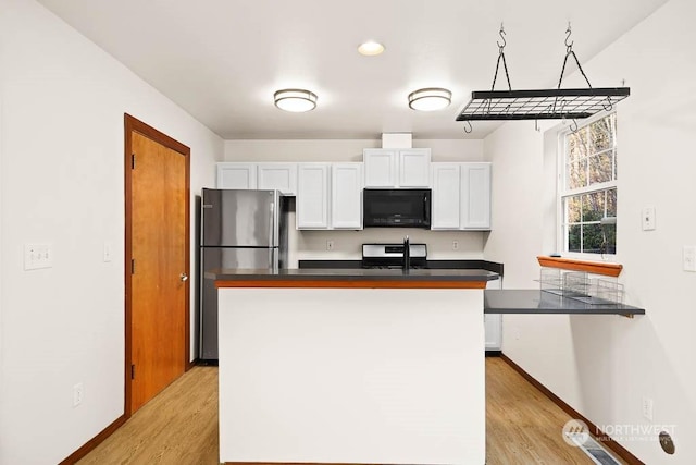 kitchen featuring a center island, stainless steel appliances, white cabinetry, and light hardwood / wood-style floors