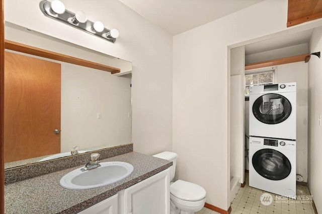 bathroom featuring tile patterned floors, vanity, toilet, and stacked washer / dryer