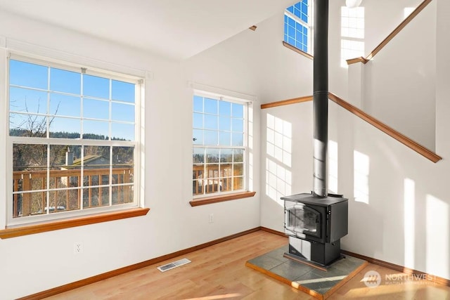 living room with hardwood / wood-style floors, a wood stove, and lofted ceiling