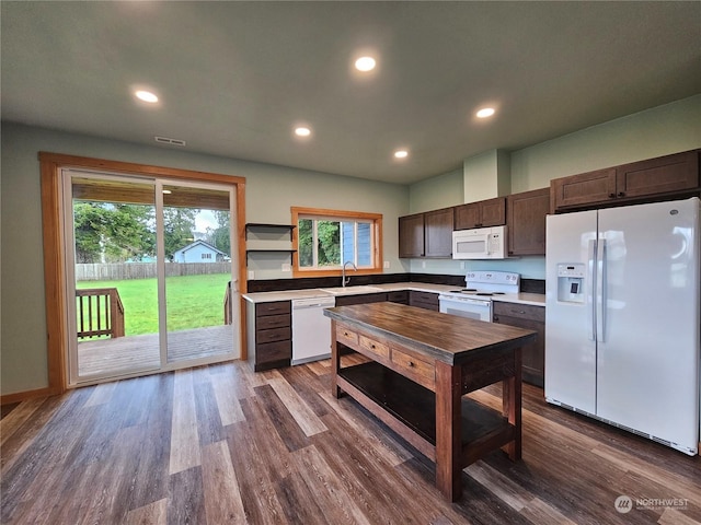 kitchen featuring dark brown cabinetry, dark hardwood / wood-style flooring, white appliances, and sink