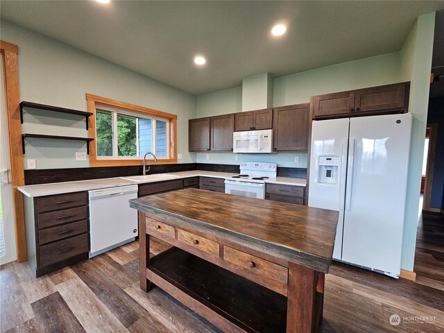 kitchen featuring white appliances, dark brown cabinetry, sink, hardwood / wood-style flooring, and a kitchen island