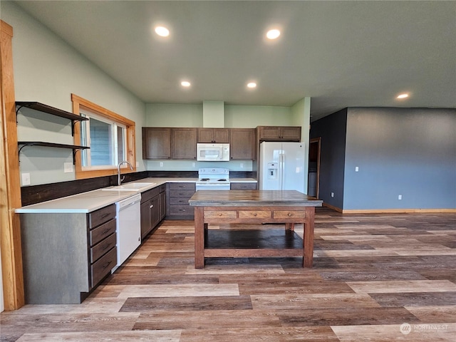 kitchen with sink, a center island, light hardwood / wood-style flooring, white appliances, and dark brown cabinets