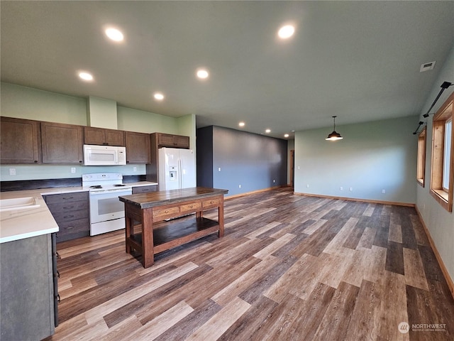 kitchen with sink, a barn door, decorative light fixtures, white appliances, and hardwood / wood-style flooring