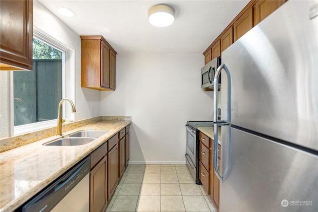 kitchen with light stone countertops, appliances with stainless steel finishes, light tile patterned flooring, and sink