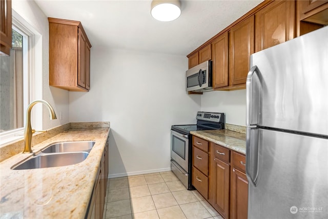 kitchen featuring light tile patterned flooring, appliances with stainless steel finishes, light stone counters, and sink