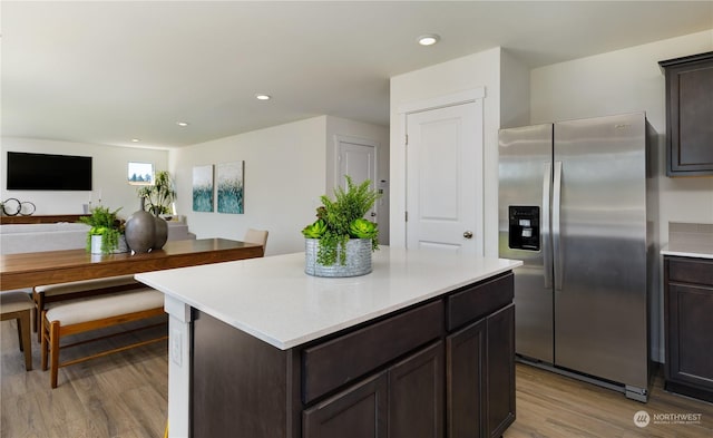 kitchen with stainless steel fridge, light wood-type flooring, a kitchen island, and dark brown cabinets