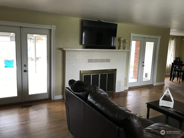 living room featuring hardwood / wood-style floors, plenty of natural light, a fireplace, and french doors