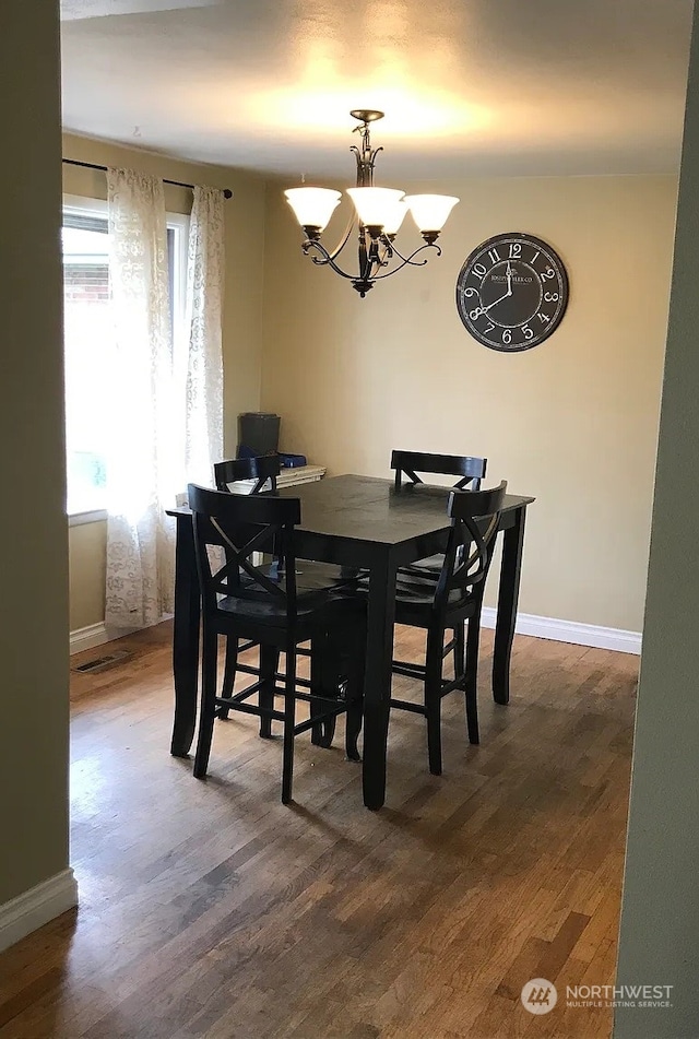 dining room with dark hardwood / wood-style flooring and an inviting chandelier