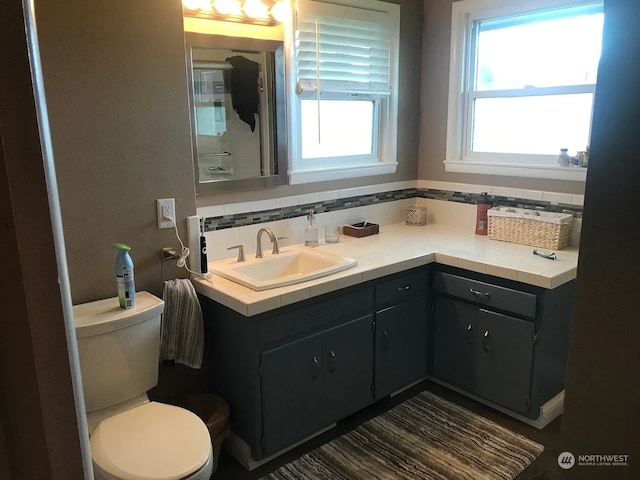 bathroom with decorative backsplash, vanity, and toilet