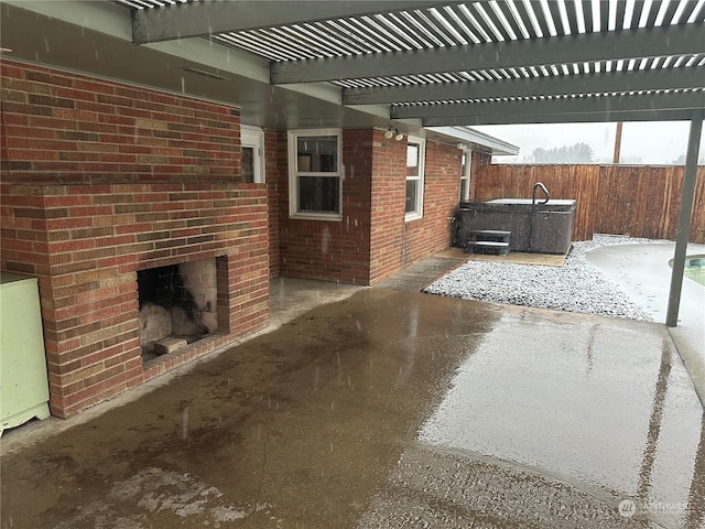 view of patio / terrace with a hot tub, a pergola, and a brick fireplace