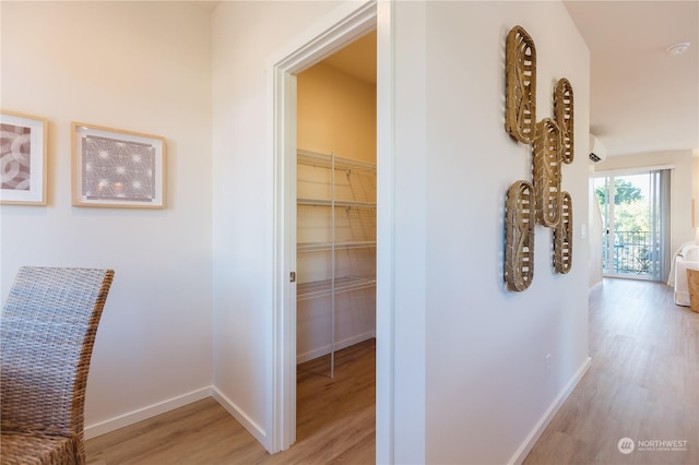 corridor featuring a wall unit AC and light wood-type flooring