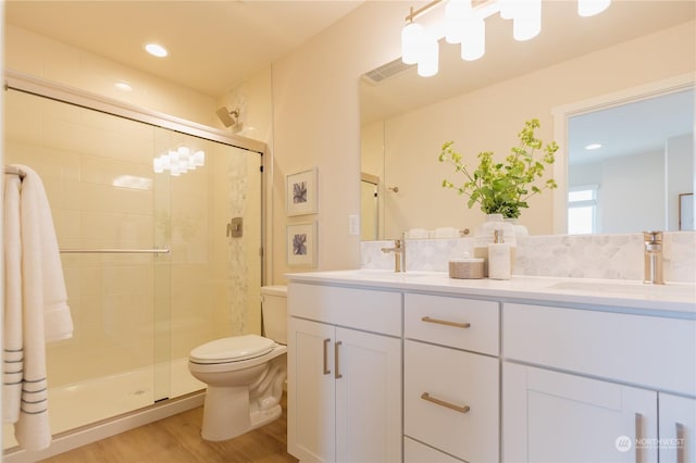 bathroom featuring hardwood / wood-style flooring, vanity, toilet, and a shower with shower door