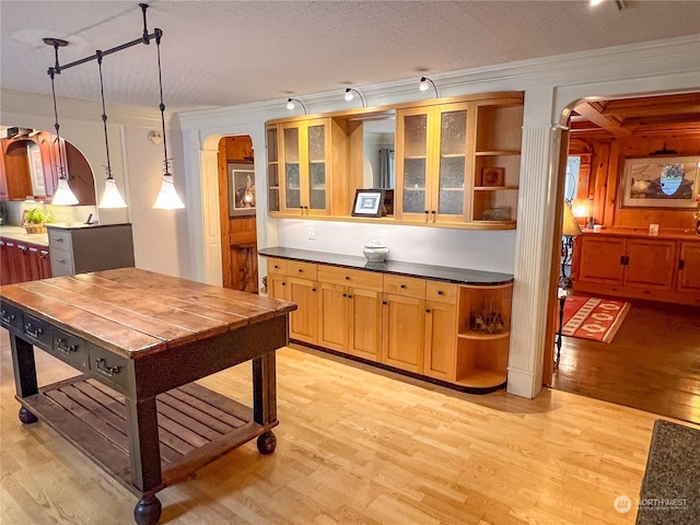 7251 Oak Bay Rd, Port Ludlow, WA 98365 - kitchen featuring arched walkways, open shelves, crown molding, light wood finished floors, and glass insert cabinets