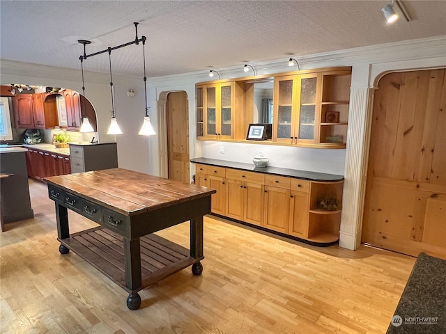 kitchen featuring hanging light fixtures, light hardwood / wood-style floors, track lighting, a textured ceiling, and ornamental molding