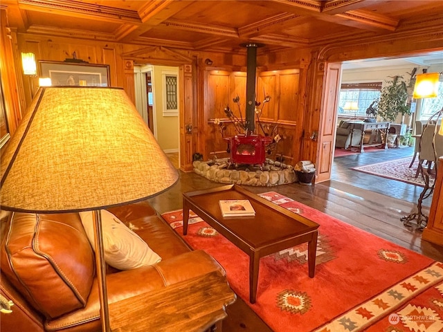 living room with beam ceiling, a wood stove, dark wood-type flooring, coffered ceiling, and wood walls