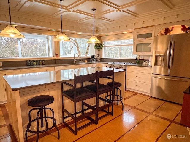 kitchen with a kitchen bar, stainless steel refrigerator with ice dispenser, a kitchen island, sink, and white cabinetry