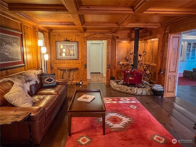 living room featuring a wood stove, dark wood-type flooring, coffered ceiling, wooden walls, and beam ceiling