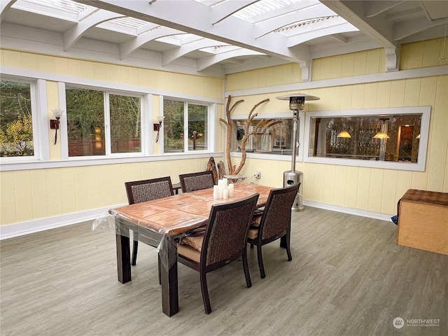 dining space featuring wood walls, beam ceiling, and wood-type flooring