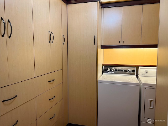 clothes washing area with cabinets and washer and dryer