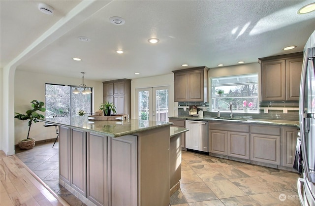 kitchen with a wealth of natural light, a center island, stainless steel appliances, and sink