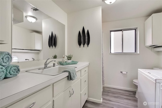 bathroom featuring vanity, toilet, wood-type flooring, and washing machine and dryer