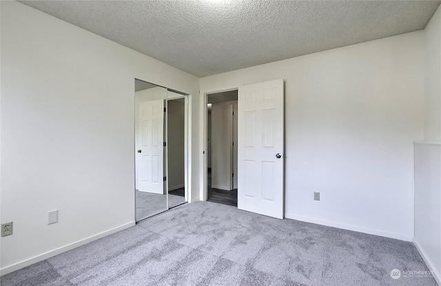 unfurnished bedroom with carpet floors, a textured ceiling, and a closet