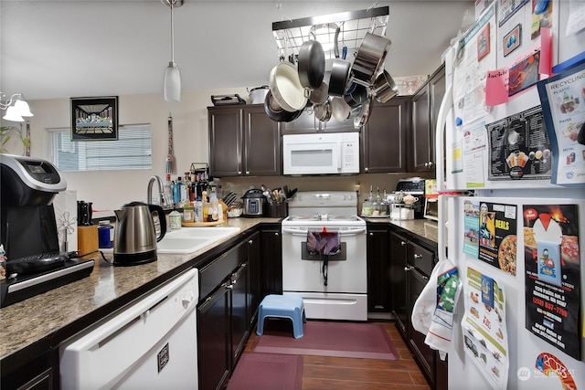 kitchen featuring dark brown cabinets, white appliances, decorative light fixtures, and dark stone countertops