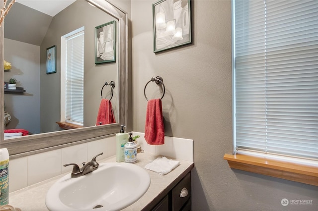 bathroom featuring decorative backsplash, vanity, and vaulted ceiling