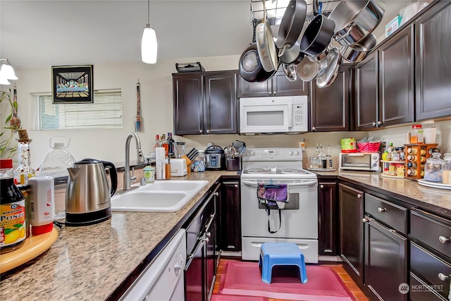 kitchen featuring pendant lighting, dark brown cabinets, white appliances, and sink