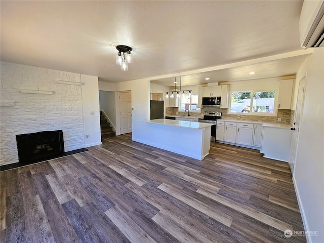 kitchen with appliances with stainless steel finishes, dark hardwood / wood-style flooring, sink, pendant lighting, and white cabinetry