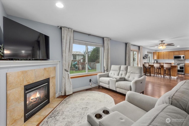 living room with ceiling fan, a fireplace, and light hardwood / wood-style floors