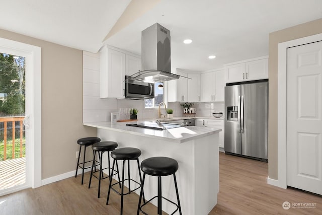 kitchen featuring appliances with stainless steel finishes, island range hood, white cabinetry, and light hardwood / wood-style floors